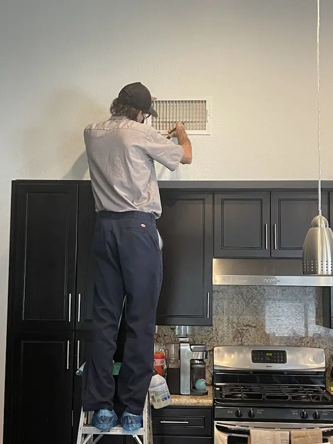 Technician inspecting an air vent during HVAC service in Sunset Hills